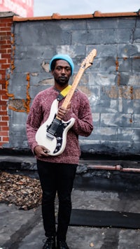 a man holding a guitar in front of a building